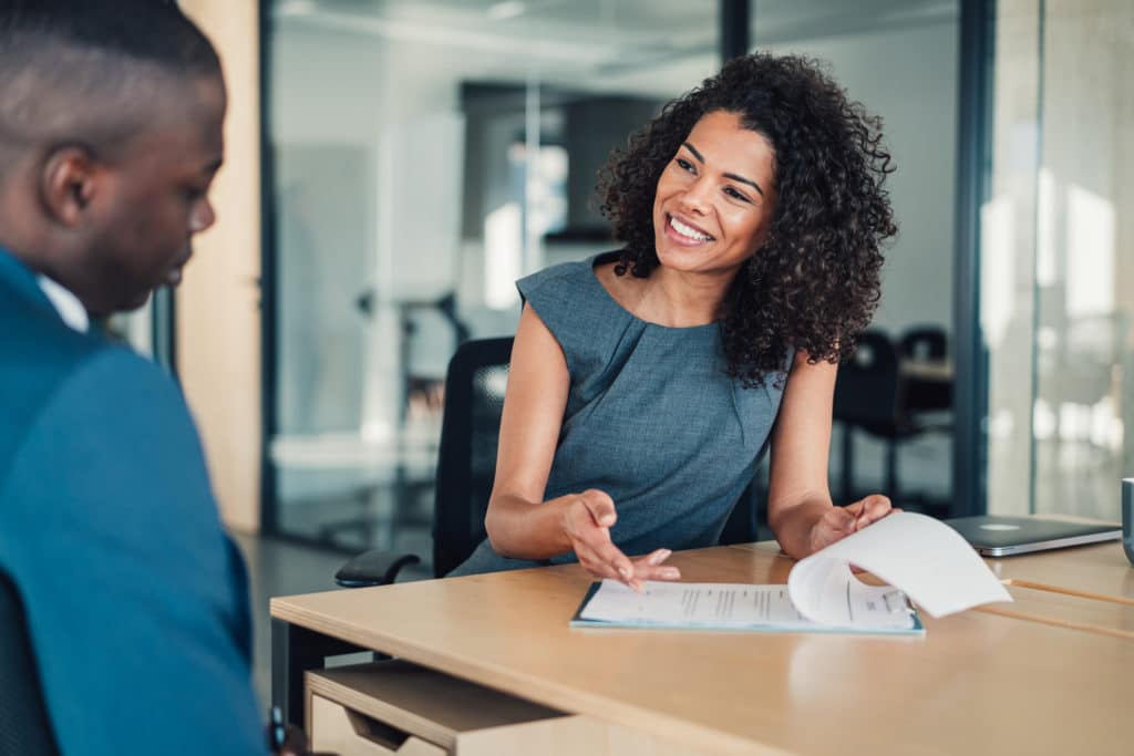 Shot of two business persons filling in paperwork in the office. Businessman and businesswoman signing a document in board room.